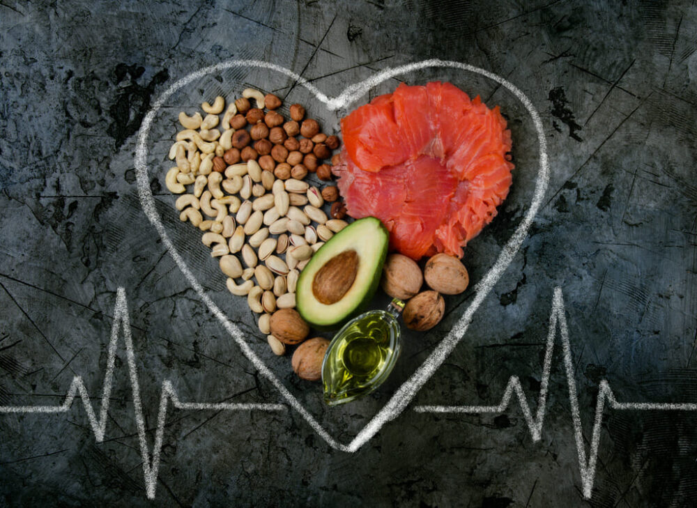 a heart beat drawn with chalk, with nuts, salmon, avocado and oil in the middle of the heart