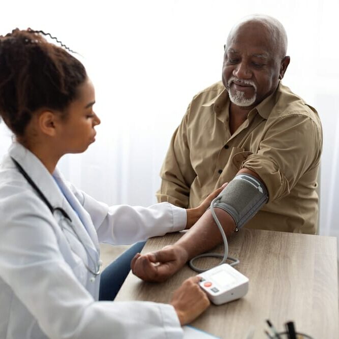 A doctor monitoring a patient's blood pressure by using a blood pressure monitor